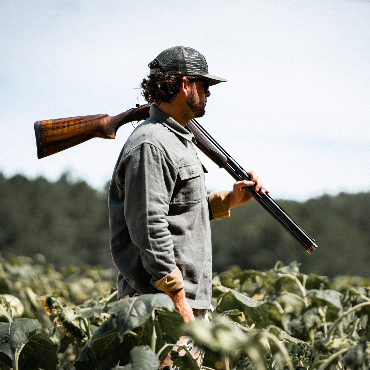Guy walking through field with shotgun on shoulder