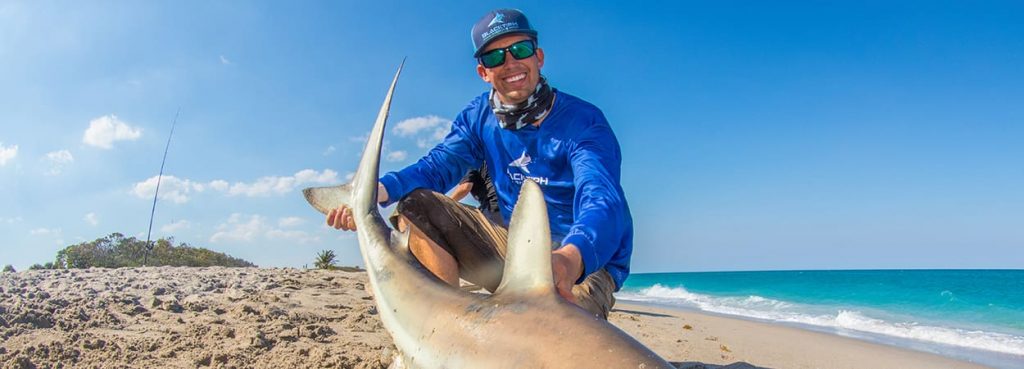 Man smiling at catching a large fish.