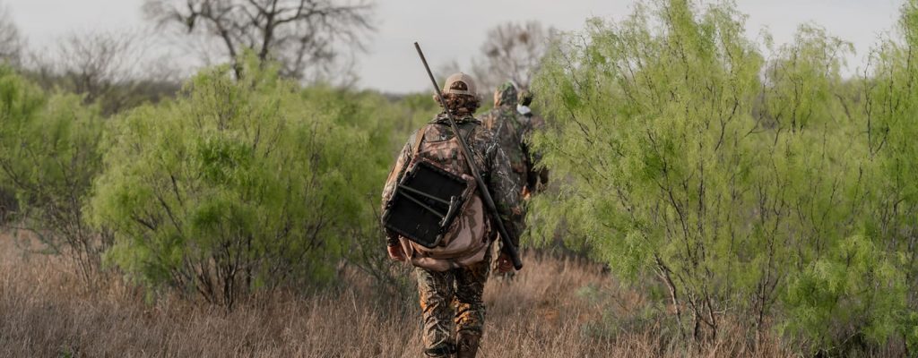 People walking with hunting gear.