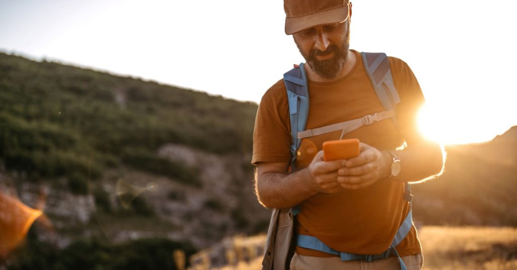 man hiking looking at phone