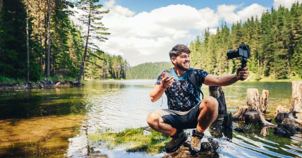 influencer in creek holding camera