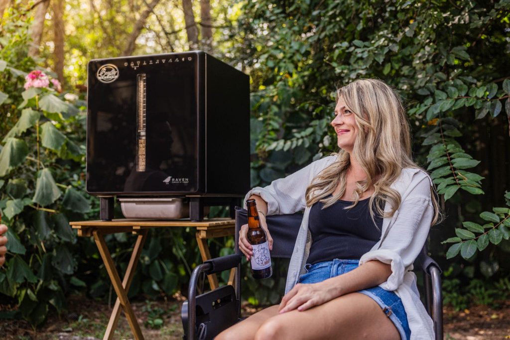 Woman sitting next to the Raven smoker drinking a beer