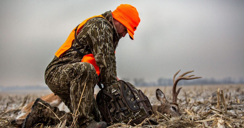 man kneeling next to deer